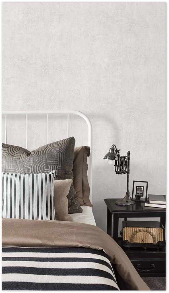 Light grey plaster texture wallpaper in a bedrrom with patterned and striped pillows   18 Mar 2015 --- Striped and patterned pillows and blanket on bed --- Image by   Hero Images Corbis